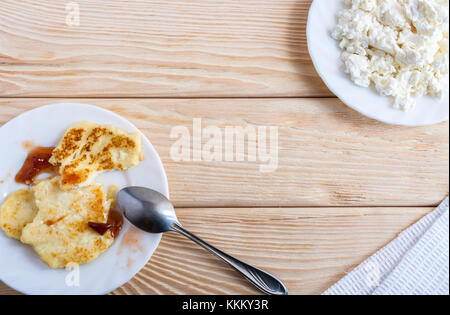 Zwei weiße Platten mit Quark, Käsekuchen mit Metall Löffel und Stück Stoff Serviette auf Holztisch mit kopieren. Stockfoto