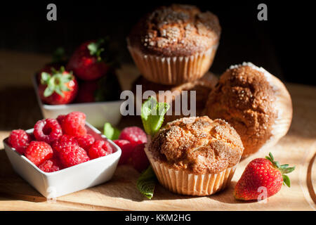 Hausgemachte Muffins mit frischen Erdbeeren und Himbeeren auf hölzernen Schreibtisch. siehe Serie. Stockfoto