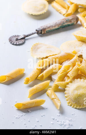 Hausgemachte Ravioli und garganelli Pasta mit Mehl und hölzernen Rolle über hellblau Holz- Hintergrund. selektive Fokus Stockfoto