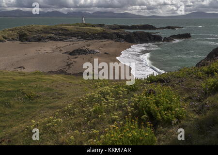 Schöne sandige Buchten an der Spitze des Ynys Llanddwyn Island über Twr Bach alten Leuchtturm suchen, mit Snowdonia darüber hinaus. Anglesey. Stockfoto