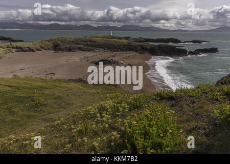 Schöne sandige Buchten an der Spitze des Ynys Llanddwyn Island über Twr Bach alten Leuchtturm suchen, mit Snowdonia darüber hinaus. Anglesey. Stockfoto