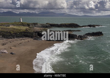 Schöne sandige Buchten an der Spitze des Ynys Llanddwyn Island über Twr Bach alten Leuchtturm suchen, mit Snowdonia darüber hinaus. Anglesey. Stockfoto