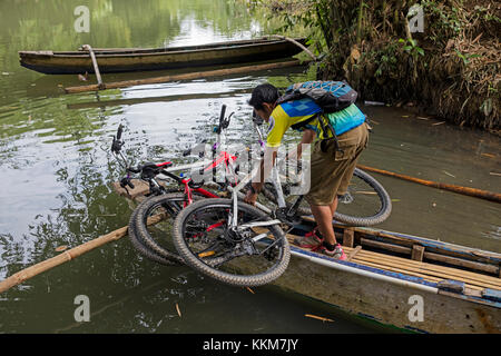 Radfahren in Indonesien Reiseführer Vermittlung von Fahrrädern in kleinen Boot vor der Überquerung eines Flusses auf der Insel Lombok. Stockfoto
