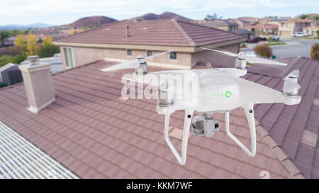 Unbemannte Luftfahrzeuge (UAV) quadcopter Drohne in der Luft über Haus Inspektion des Daches. Stockfoto