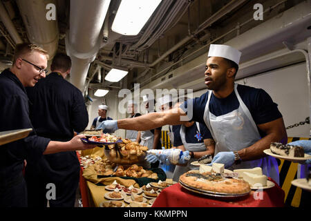 171123-N-Z. B. 687-0077 PAZIFISCHEN OZEAN (Nov. 23, 2017) der Maschinist Mate 1. Klasse Rickie Carter, aus Birmingham, Ala., serviert das Dessert zu Matrosen während des Thanksgiving Dinner auf das Chaos Decks an Bord der Flugzeugträger USS Theodore Roosevelt. Theodore Roosevelt ist zur Unterstützung der Maritime Security Operations und Theater Sicherheit Zusammenarbeit bereitgestellt werden. (U.S. Marine Foto von Aviation Ordnanceman Airman Shawn Murphy/Freigegeben) Stockfoto