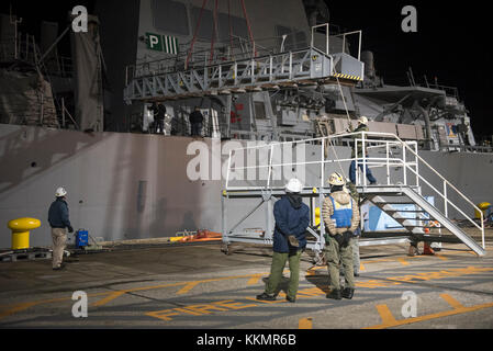 YOKOSUKA, Japan (November 24, 2017) - Arbeiter der Stirn von der Arleigh-Burke-Klasse Lenkwaffen-zerstörer USS Fitzgerald (DDG62) vor vom Pier in Flotte Aktivitäten (FLEACT) Kamakura, 07.11.24, zum Abschleppen Heavy lift Transportschiff Transshelf zu erfüllen. Transshelf transport Fitzgerald in Pascagoula, Mississippi für Reparaturen. Stockfoto