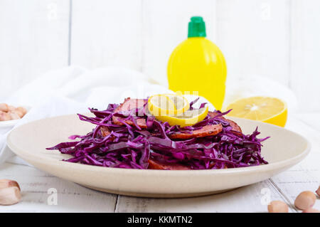 Salat von Rotkohl, Salami, Erdnüsse auf weißem Holz- Hintergrund Stockfoto