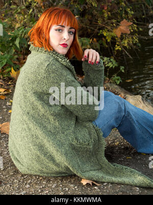 Schöne rothaarige Mädchen im Park neben dem See im Herbst Stockfoto