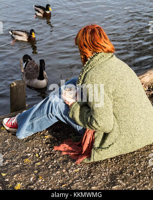 Schöne Mädchen im Park feeding ducks Stockfoto