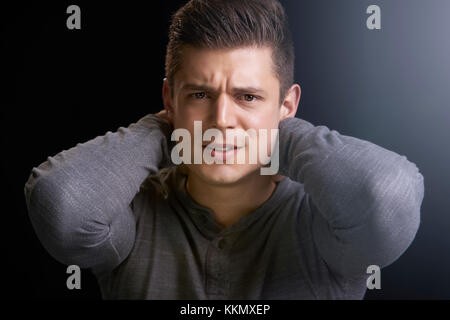 Portrait von wütenden jungen weißen Mann mit den Händen den Nacken Stockfoto