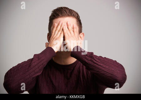 Porträt einer jungen weißen Mann mit Händen bedeckte sein Gesicht Stockfoto