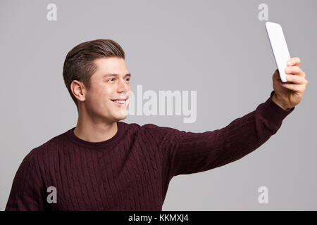 Ein lächelnder junger Mann eine selfie mit seinem Smartphone Stockfoto