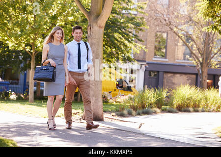 Geschäftsmann und Geschäftsfrau zu Fuß zur Arbeit durch City Park Stockfoto