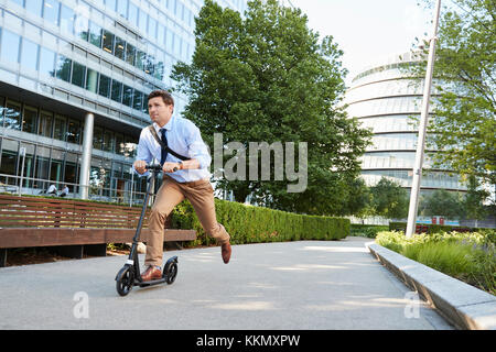 Junge Unternehmer Pendeln zur Arbeit durch die Stadt auf Scooter Stockfoto