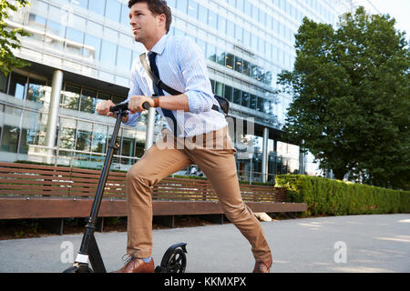 Junge Unternehmer Pendeln zur Arbeit durch die Stadt auf Scooter Stockfoto