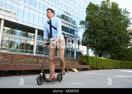 Junge Unternehmer Pendeln zur Arbeit durch die Stadt auf Scooter Stockfoto