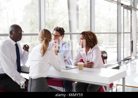 Junge Unternehmen, die Menschen sprechen über Kaffee in einer modernen Lobby Stockfoto