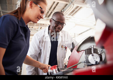 Ingenieur mit weiblichen Lehrling, wie Maschinen zu bedienen, in der Nähe Stockfoto