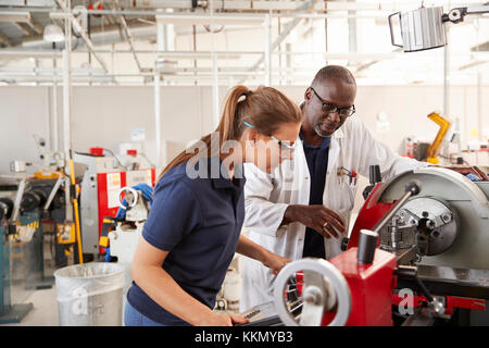 Ingenieur mit weiblichen Lehrling, wie eine Maschine zu bedienen. Stockfoto