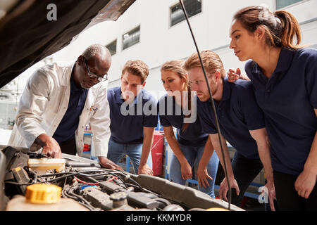 Mechaniker anweisen Praktikanten auf, die ein Auto Motor, niedrigen Winkel Stockfoto