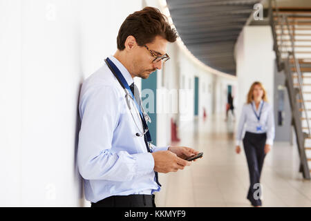 Portrait von jungen männlichen Arzt mit Stethoskop und Smartphone Stockfoto