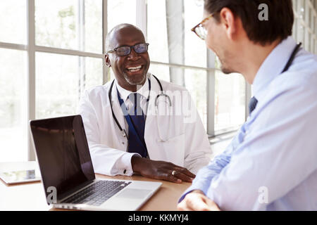 Zwei ältere Mitarbeiter im Gesundheitswesen in Absprache lachen Stockfoto