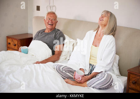 Rentnerehepaar tragen Schlafanzug im Bett sitzen Tee trinken. Stockfoto