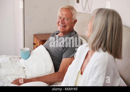 Rentnerehepaar tragen Schlafanzug im Bett sitzen Tee trinken. Stockfoto