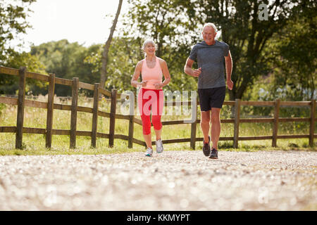 Gesunde ältere Paar beim Laufen durch die Landschaft zusammen Stockfoto