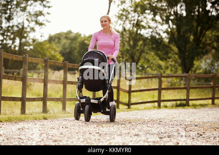 Mutter der Ausübung durch Ausführen Während schieben Kinderwagen Stockfoto