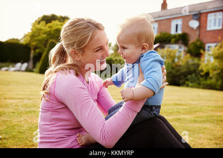 Mutter spielt im Garten mit Baby Sohn Stockfoto