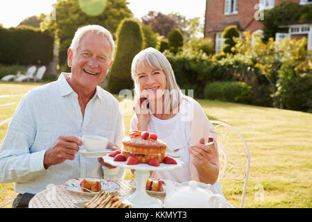 Rentnerehepaar genießen Nachmittagstee im Garten zu Hause Stockfoto