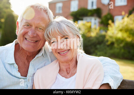 Senior Paar Sitzen auf der Gartenbank in der Abendsonne Stockfoto