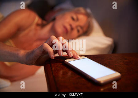 Schlaflose ältere Frau im Bett in der Nacht überprüfen Mobiltelefon Stockfoto