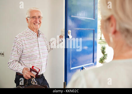 Lächelnd senior Paar verlassen Haus, Blick über die Schulter Stockfoto