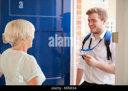 Ältere Frau öffnet die Tür zu den männlichen care Worker zeigt seine ID Stockfoto
