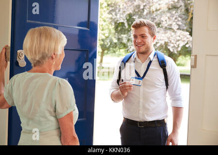 Ältere Frau öffnet die Tür zu den männlichen care Worker zeigt seine ID Stockfoto