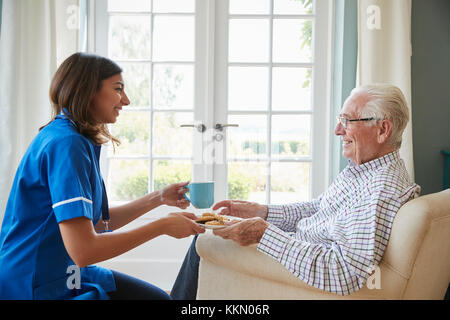 Krankenschwester mit einer Tasse Kaffee zu einem älteren Mann zu Hause, in der Nähe Stockfoto