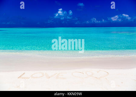 Wort Liebe auf Sand in Malediven geschrieben mit der Lagune im Hintergrund. Stockfoto