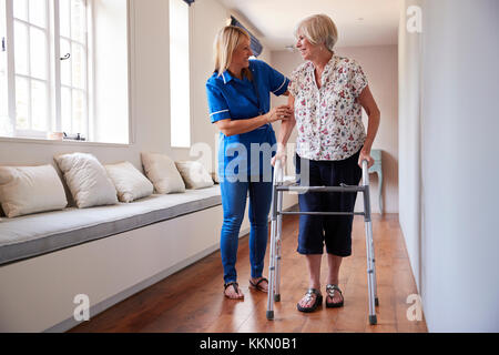 Krankenschwester helfen ältere Frau mit einer Gehhilfe Stockfoto