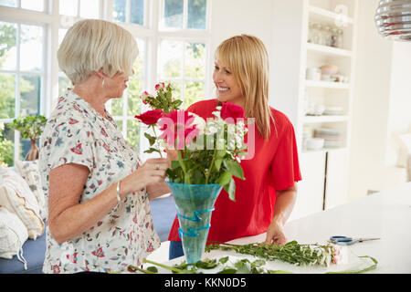 Ältere Frau und erwachsene Tochter Blumen zu Hause anordnen Stockfoto