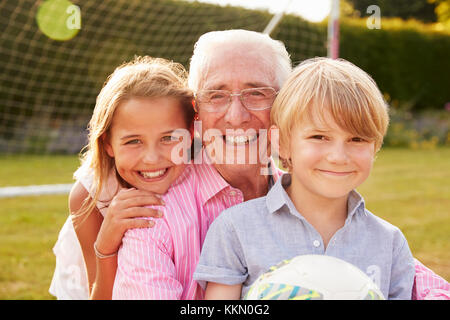 Älterer Mann und Enkel holding Ball lächelnd in die Kamera Stockfoto