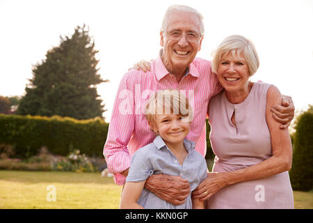 Senior Paar und Enkel umarmen und lächelnd in die Kamera Stockfoto