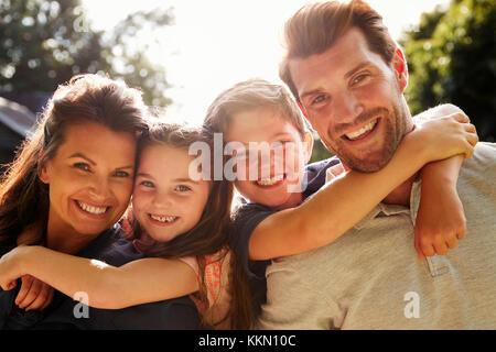 Portrait von Eltern, Kindern Huckepack im Garten Stockfoto