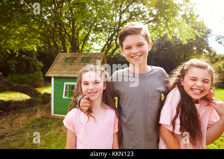 Portrait von Kindern im Garten Neben Playhouse stehend Stockfoto