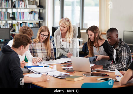 Lehrerin Arbeiten mit Studenten in Bibliothek Stockfoto