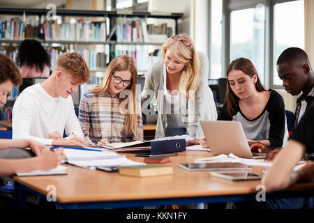 Lehrerin Arbeiten mit Studenten in Bibliothek Stockfoto