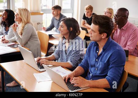 Ältere Studierende am Schreibtisch sitzen in der Erwachsenenbildung Klasse Stockfoto