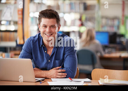 Von ausgewachsenen männlichen Kursteilnehmer mit Laptop in der Bibliothek Portrait Stockfoto