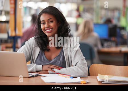 Der geschlechtsreifen weiblichen Kursteilnehmer mit Laptop in der Bibliothek Portrait Stockfoto